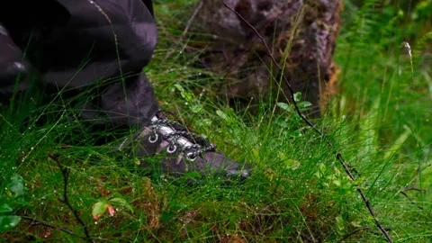 A person steps on the grass from which dew falls in slow motion. Hiking boots. Stock Footage 197340022