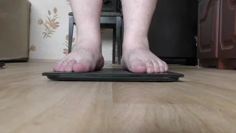 A person steps on a scale to find out his weight Stock Footage 154052660