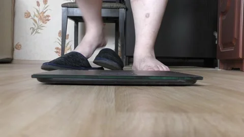 A person steps on a scale to find out his weight Stock Footage 154445445