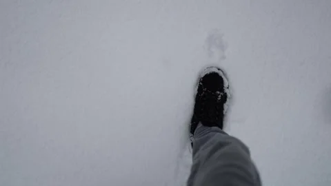 A person steps through freshly fallen snow, their black shoes contrasting agains Stock Footage 298257348