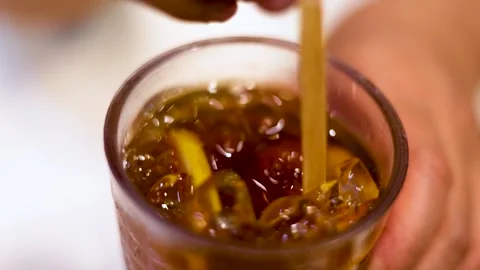 Person stirring refreshing iced tea with lemon slices and ice cubes in glas.. Stock Footage 332720189