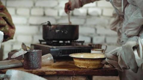 Person Stirs Soup While Another Retrieves Bowl in Shelter 動画素材 347088915