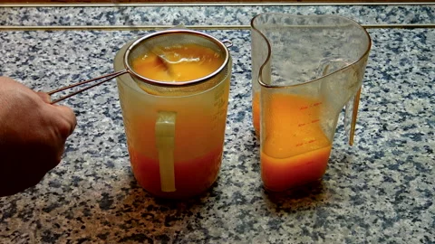 A person is straining freshly squeezed fruit juice Stock Footage 141160349