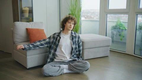 Person stretches while sitting on floor next to couch in modern room with plants Stock Footage 344921790