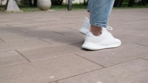 Person strolling outdoors in comfortable white footwear. Low angle shot of .. Video stock 339861480