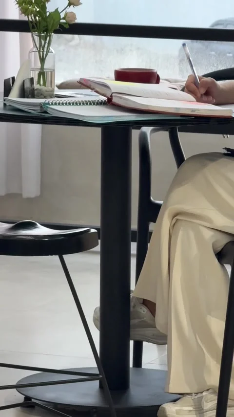 Person studying and writing in notebook at cafe table, vertical view Stock Footage 345160340