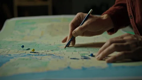 Person studying a map while marking locations with pins and a pencil during Stock Footage 301407031