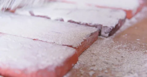 Person sweeps away white plaster residue from cast bricks Stock Footage 186333353