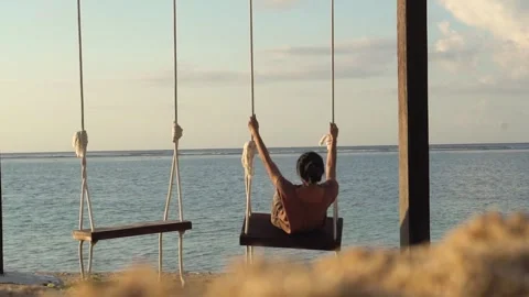 Person on Swing Facing Ocean at Sunset Stock Footage 277025925