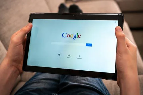 Person with tablet using Google search app to search the web. Stock Photos