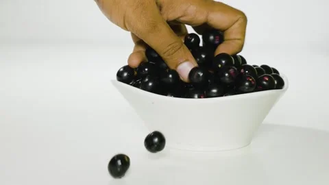 A person takes Java plum fruits from a bowl front pulling 4k short Stock Footage 252207031