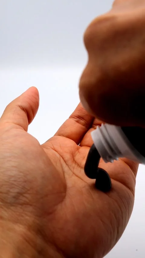 A person takes out a charcoal-based facial cleanser into their hand. Stock Footage 335347592