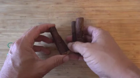 Person taking apart a bundle of fresh licorice root sticks over a rustic wo.. Stockbeeldmateriaal 340549278