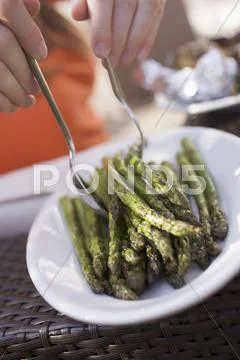Person taking grilled asparagus from a plate Stock Photos