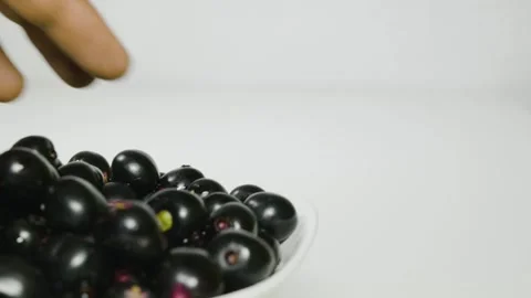 A person is taking Java plum fruits from a bowl on that time fruits fall down 4k Video stock 252206998