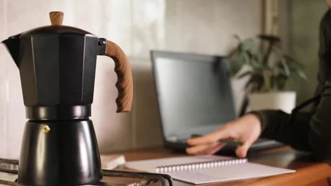 Person taking notes and writing in notepad near moka pot coffee maker Stock Footage 344058199
