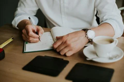 Person taking notes in a notebook while working from home Stock Photos