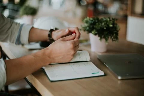Person taking notes in a notebook while working from home Stock Photos
