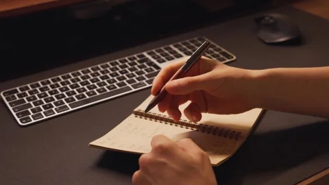 Person taking notes on a notepad at a desk while working Stock Footage 341038788