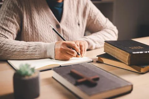 Person taking notes while reading an open Bible at a desk, pencil and journ.. Foto stock
