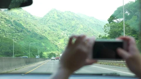 A person taking a photo of the green mountains in Oahu, Hawaii, while drivi.. Stock Footage 284078053