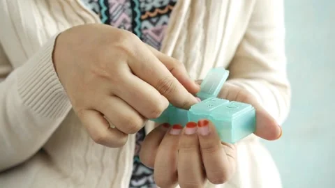 A person taking pills from weekly pill box. daily medicine Dietary vitamin 스톡 동영상 336586477
