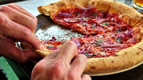 Person taking a slice of Neapolitan pepperoni pizza at a restaurant table Stock Footage 341541218