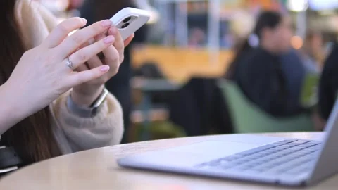 Person taps smartphone while laptop rests on table Stock Footage 342027901