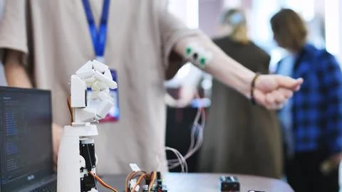 Person testing a bionic robotic hand controlled by muscle sensors connected to Stock Photos