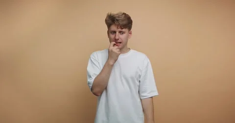 Person thinking and reflecting in a simple setting with orange wall backgro.. Видео 328247071