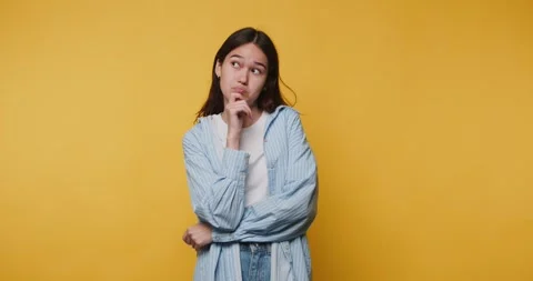 Person thinks while posing in front of a yellow background in a studio settin Stock-Footage 328248088