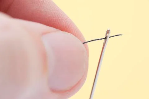 Person threading a needle with yarn Stock Photos
