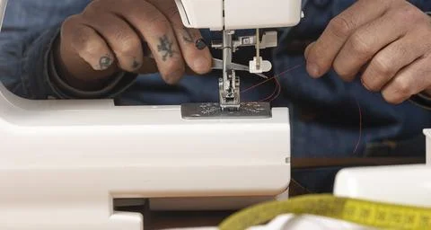 Person threading a sewing machine with red thread Stock Photos
