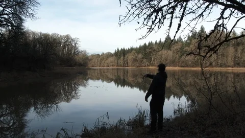 Person Throwing Object Into Forest Lake Stock Footage 99845253