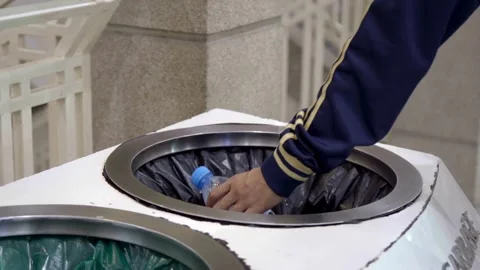 Person throwing a plastic bottle into a trash bin Stock Footage 331989694