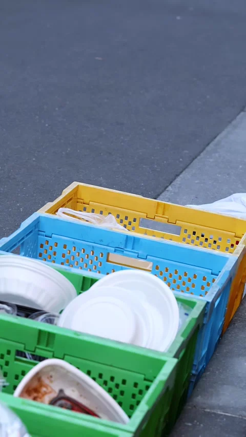 Person Throwing Trash into Plastic Recycling Crates on Tokyo Sidewalk Stock Footage 343594611