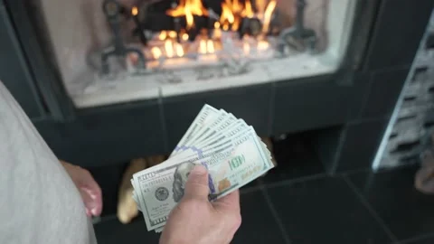 Person throws 100 dollar bills in fireplace and the money burns Stock Footage 231535764