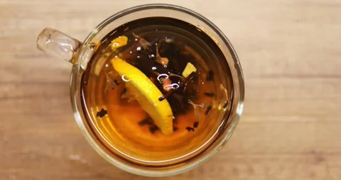 Person throws fresh lemon slice into transparent mug with aromatic black tea Video stock 290889345