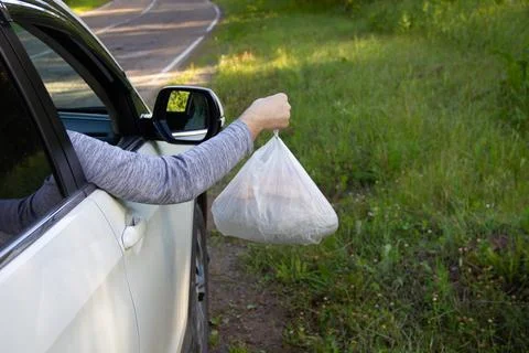 A person throws garbage from a car on the side of the road Stock Photos