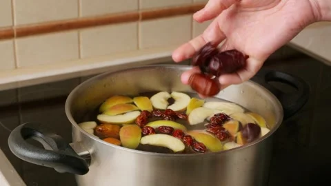 A person throws a handful of dried dates into a saucepan Stock Footage 308157761