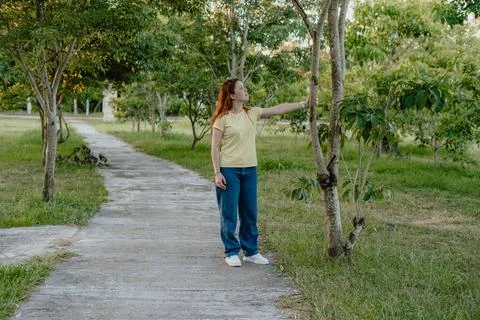 Person touching tree branches by a pathway, mindful connection with nature Foto stock