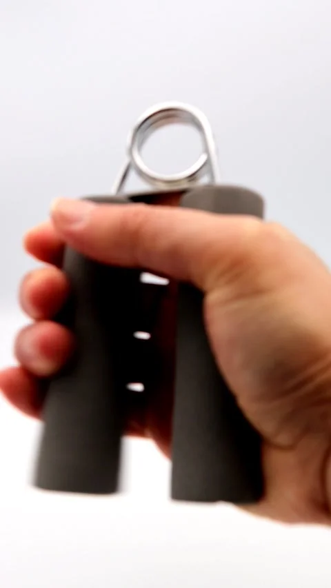 A person training their grip strength with a hand grip. Stock Footage 336521133