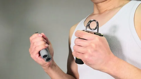 A person training their grip strength with a hand grip. Vidéo 336674650
