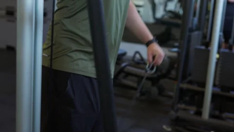 Person training upper body muscles using a cable pulley machine in a fitness cen Stock Footage 339598080