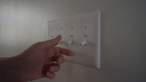 A person turn a light switch on during the day inside a home Stock-Footage 128918624