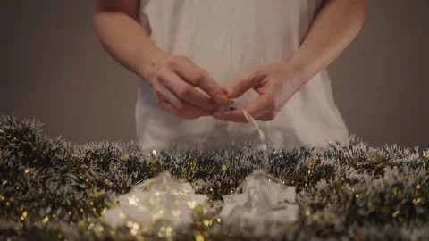 Person turning on battery-powered string lights shaped like small white houses Stock Footage 323449919