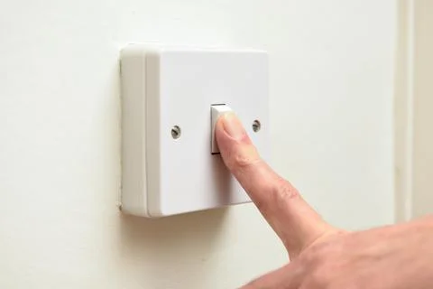 Person turning off light switch to save on energy bills and waste of electric Stock Photos