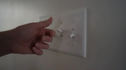 A person turns off a light switch during the day inside a home Stock-Footage 128918590