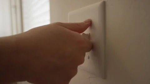 A person turns off a light switch during the day inside a home Stock Footage 128918696