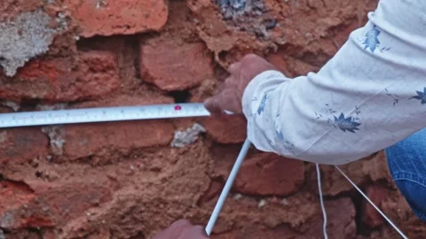 Person tying string line to nail on construction site. day time, tilt down Stock Footage 312877832